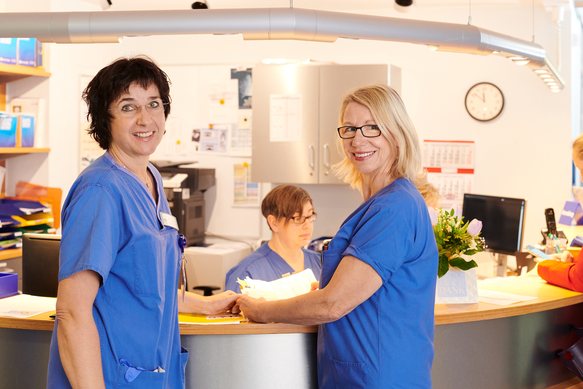 Zwei Mitarbeitinnen der IKO stehen am Tresen der Patientenanmeldung